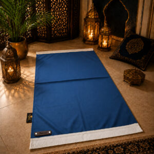 Le tapis de prière personnalisé bleu Roi Sajadah avec ses franges blanches et sa lanière en cuir véritable couleur chocolat.