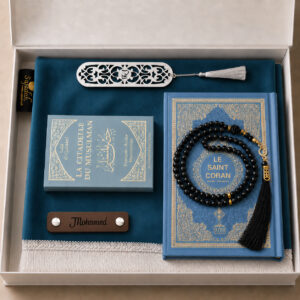 Le coffret tapis de prière de couleur bleu Azur Sajadah avec ses franges blanches, sa personnalisation en cuir couleur chocolat, son tasbih classique, son livret "La citadelle du Musulmans" et son Saint Coran de couleur blanc.