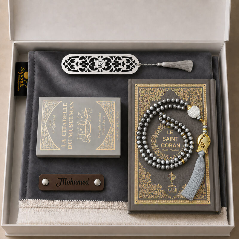 Das personalisierte Sajadah Gebetsteppich-Geschenkset in Schiefergrau mit einem Teppich mit weißen Fransen, einem Riemen aus echtem schokoladenbraunem Leder, einem Tasbih in Kristalloptik, einem Exemplar von „Die Festung des Muslims“ und einem Koran.