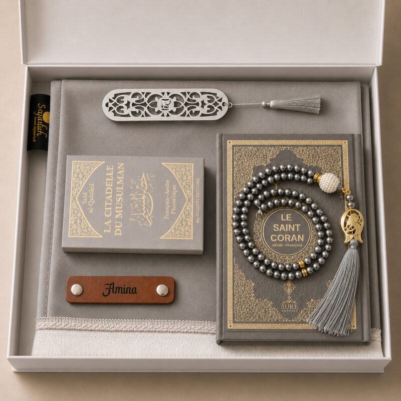 Das personalisierte Sajadah Gebetsteppich-Geschenkset in Silbergrau mit einem Teppich mit weißen Fransen, einem Riemen aus echtem braunem Leder, einem Tasbih in Kristalloptik, einem Exemplar von „Die Festung des Muslims“ und einem Koran.