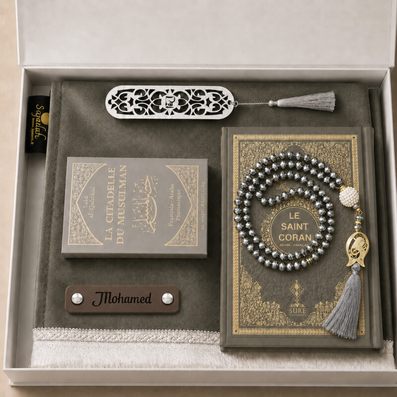 Das personalisierte Sajadah Gebetsteppich-Geschenkset in Eisengrau mit einem Teppich mit weißen Fransen, einem Riemen aus echtem schokoladenbraunem Leder, einem Tasbih in Kristalloptik, einem Exemplar von „Die Festung des Muslims“ und einem Koran.
