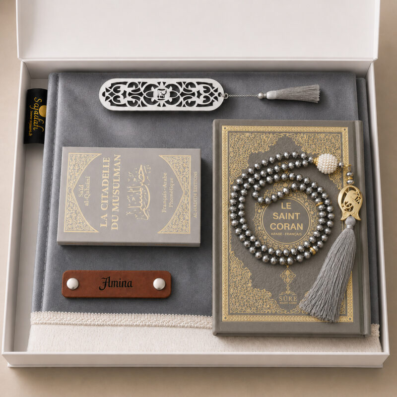 Le coffret tapis de prière personnalisé gris Plomb Sajadah avec son tapis à franges blanches, sa lanière en cuir véritable couleur marron, son tasbih effet cristal, son exemplaire de "la citadelle du musulman" et son exemplaire du "Saint Coran".