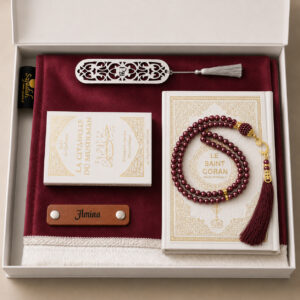 Le coffret tapis de prière de couleur rose framboise Sajadah avec ses franges blanches, sa personnalisation en cuir couleur marron, son tasbih classique, son livret "La citadelle du Musulmans" et son Saint Coran de couleur blanc.