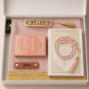 Le coffret tapis de prière de couleur rose Pale Sajadah avec ses franges dorées, sa personnalisation en cuir couleur marron, son tasbih classique, son livret 