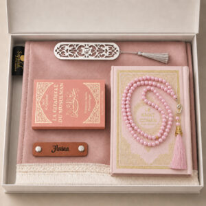 Le coffret tapis de prière de couleur rose Poudre Sajadah avec ses franges blanches, sa personnalisation en cuir couleur marron, son tasbih classique, son livret "La citadelle du Musulmans" et son Saint Coran de couleur rose.