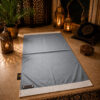 Le tapis de prière personnalisé gris Plomb Sajadah avec ses franges blanches et sa lanière en cuir véritable chocolat.