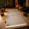 Le tapis de prière personnalisé beige Crème Sajadah avec ses franges blanches et sa lanière en cuir véritable couleur marron.