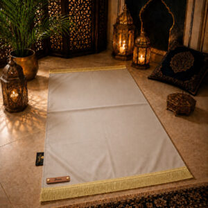 Le tapis de prière personnalisé beige Crème Sajadah avec ses franges dorées et sa lanière en cuir véritable couleur marron.