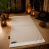 Le tapis de prière personnalisé blanc Ivoire Sajadah avec ses franges blanches et sa lanière en cuir véritable couleur chocolat.