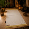 Le tapis de prière personnalisé blanc Ivoire Sajadah avec ses franges dorées et sa lanière en cuir véritable couleur marron.