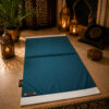 Le tapis de prière personnalisé bleu Azur Sajadah avec ses franges blanches et sa lanière en cuir véritable chocolat.
