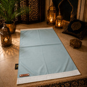 Le tapis de prière personnalisé bleu Ciel Sajadah avec ses franges blanches et sa lanière en cuir véritable marron.