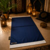 Le tapis de prière personnalisé bleu Nuit Sajadah avec ses franges blanches et sa lanière en cuir véritable chocolat.