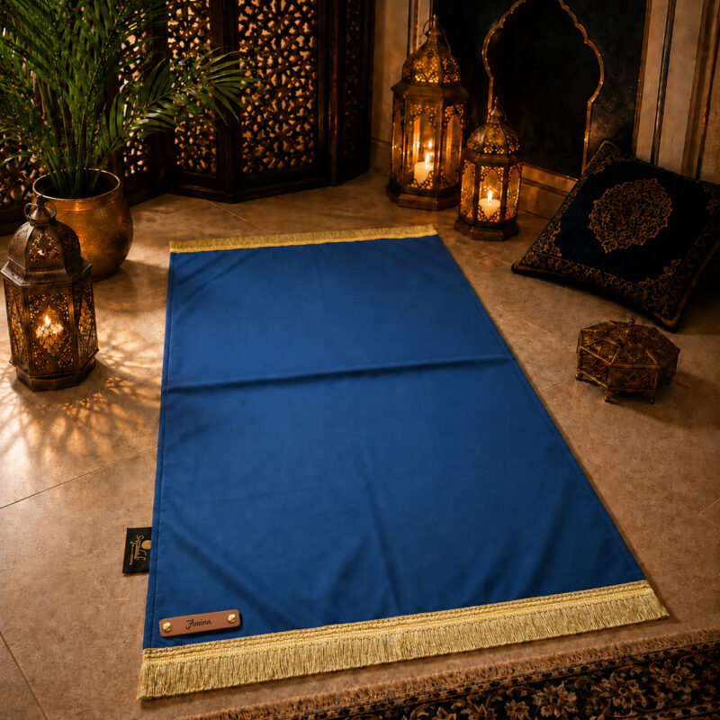 Le tapis de prière personnalisé bleu Roi Sajadah avec ses franges dorées et sa lanière en cuir véritable couleur marron.