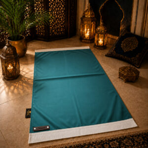 Le tapis de prière personnalisé bleu Turquoise Sajadah avec ses franges blanches et sa lanière en cuir véritable chocolat.