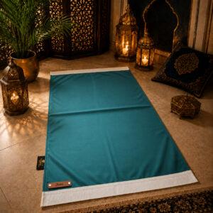 Le tapis de prière personnalisé bleu Turquoise Sajadah avec ses franges blanches et sa lanière en cuir véritable marron.