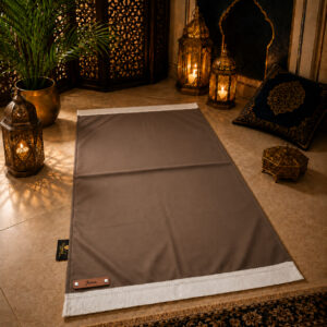 Le tapis de prière personnalisé marron Cannelle Sajadah avec ses franges blanches et sa lanière en cuir véritable marron.