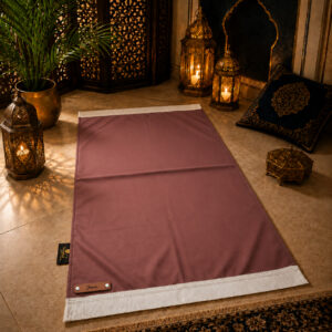 Le tapis de prière personnalisé rose Chair Sajadah avec ses franges blanches et sa lanière en cuir véritable couleur marron.