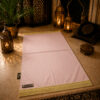 Le tapis de prière personnalisé rose Pâle Sajadah avec ses franges dorées et sa lanière en cuir véritable couleur chocolat.
