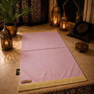 Le tapis de prière personnalisé rose Poudre Sajadah avec ses franges dorées et sa lanière en cuir véritable couleur marron.