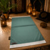 Le tapis de prière personnalisé vert Pin Sajadah avec ses franges blanches et sa lanière en cuir véritable chocolat.