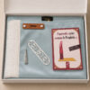 Le coffret tapis de prière enfant bleu Ciel Sajadah pour fille avec ses franges blanches et sa personnalisation en cuir véritable de couleur marron.