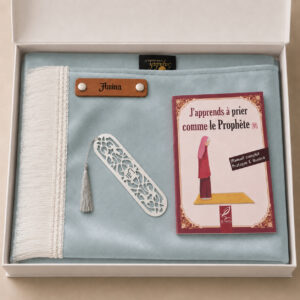 Le coffret tapis de prière enfant bleu Ciel Sajadah pour fille avec ses franges blanches et sa personnalisation en cuir véritable de couleur marron.