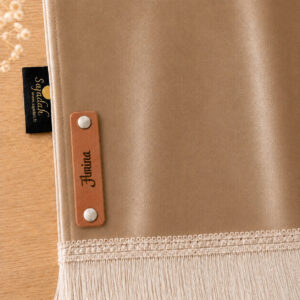 Zoom sur la personnalisation en cuir véritable de couleur marron portant votre prénom du tapis de prière Sajadah pour enfant beige Chatain.