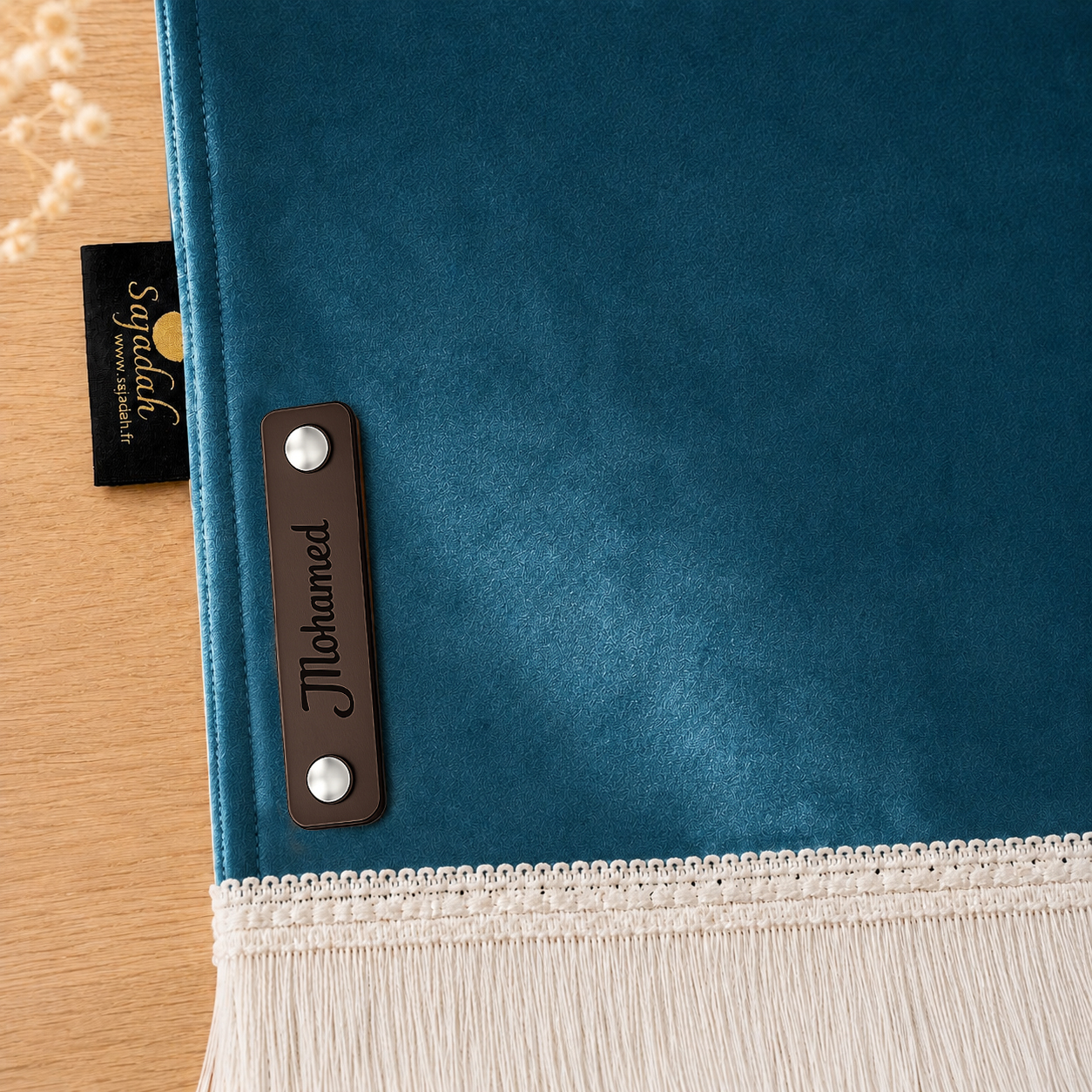 Zoom sur la personnalisation en cuir véritable de couleur chocolat portant votre prénom du tapis de prière Sajadah pour enfant bleu Azur.