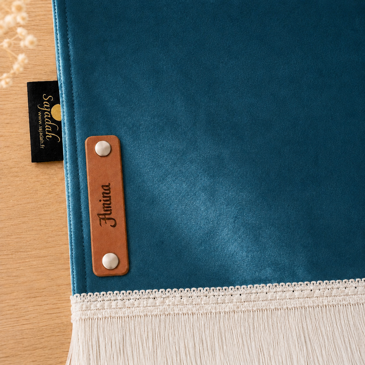 Zoom sur la personnalisation en cuir véritable de couleur marron portant votre prénom du tapis de prière Sajadah pour enfant bleu Azur.