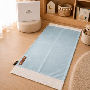 Le tapis de prière Sajadah de couleur bleu Ciel avec ses franges blanches et sa personnalisation en cuir véritable de couleur marron.