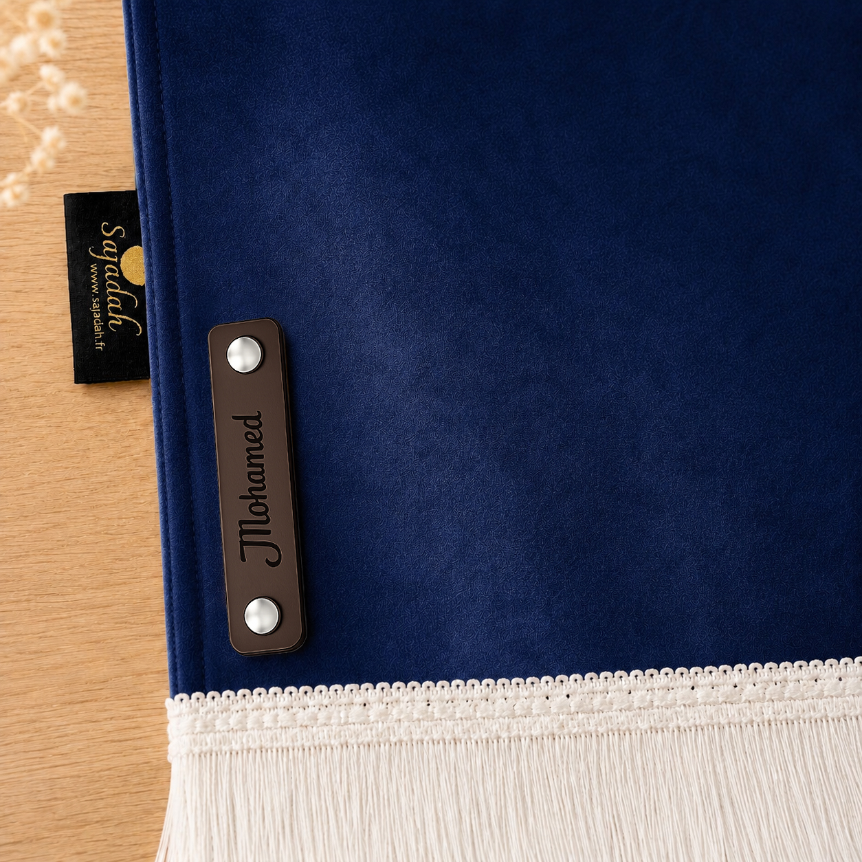 Zoom sur la personnalisation en cuir véritable de couleur chocolat portant votre prénom du tapis de prière Sajadah pour enfant bleu Nuit.