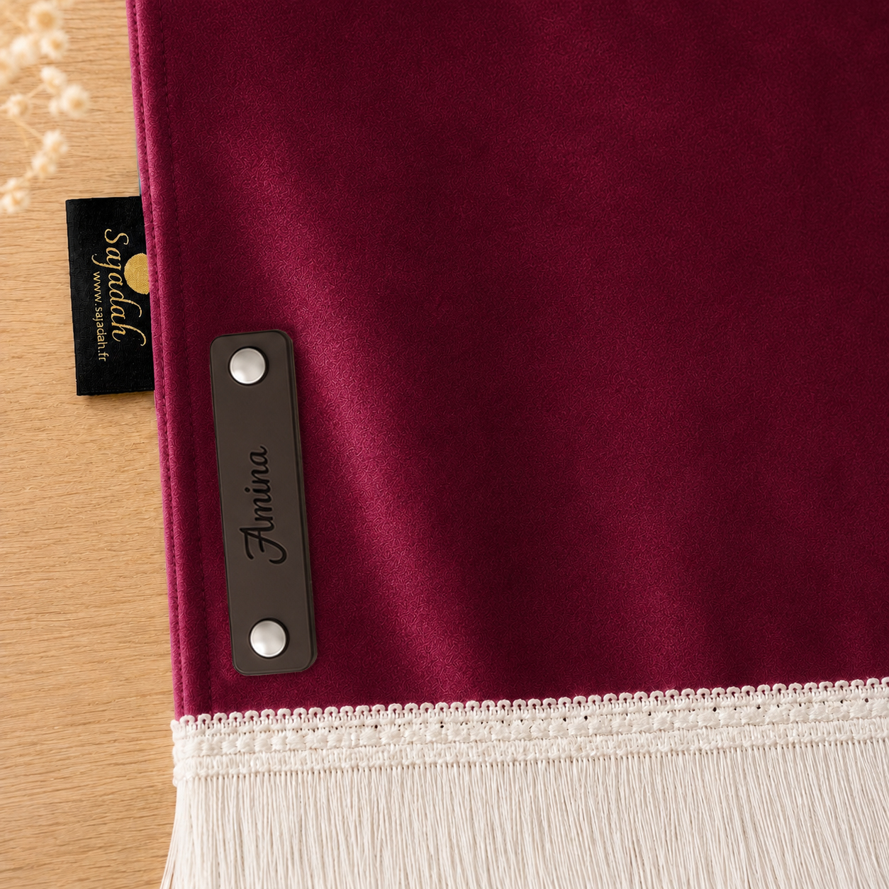 Zoom sur la personnalisation en cuir véritable de couleur chocolat portant votre prénom du tapis de prière Sajadah pour enfant rose Framboise.