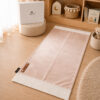Le tapis de prière Sajadah de couleur rose Pâle avec ses franges blanches et sa personnalisation en cuir véritable de couleur marron.