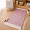 Le tapis de prière Sajadah de couleur rose Poudre avec ses franges blanches et sa personnalisation en cuir véritable de couleur marron.
