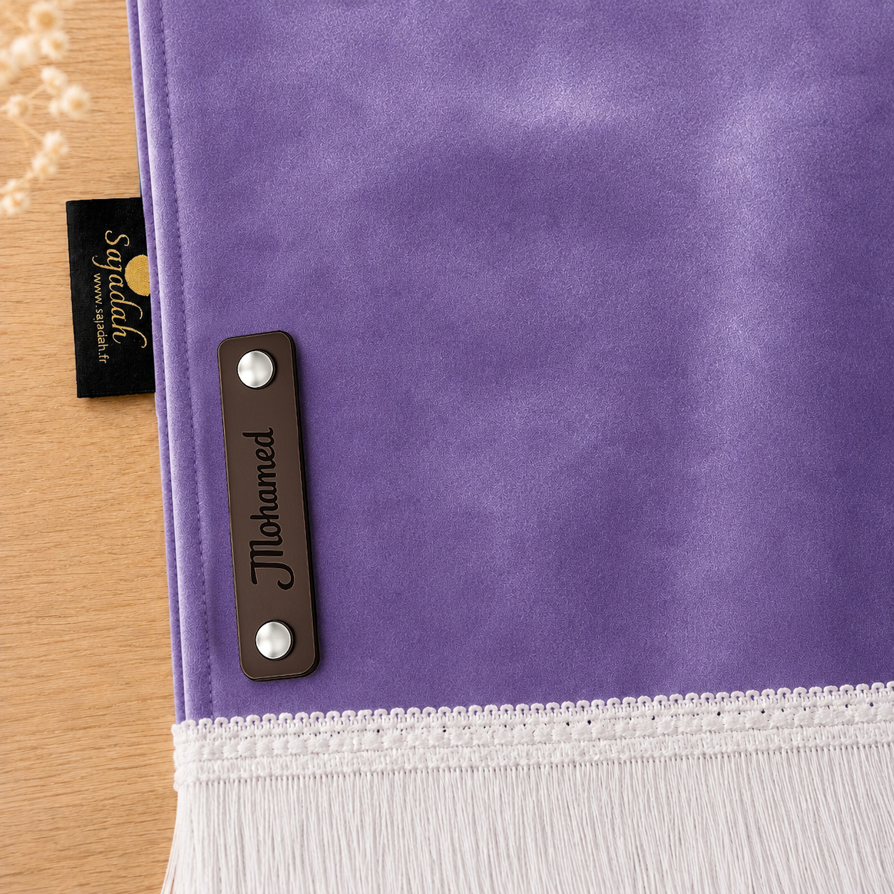 Zoom sur la personnalisation en cuir véritable de couleur chocolat portant votre prénom du tapis de prière Sajadah pour enfant violet.