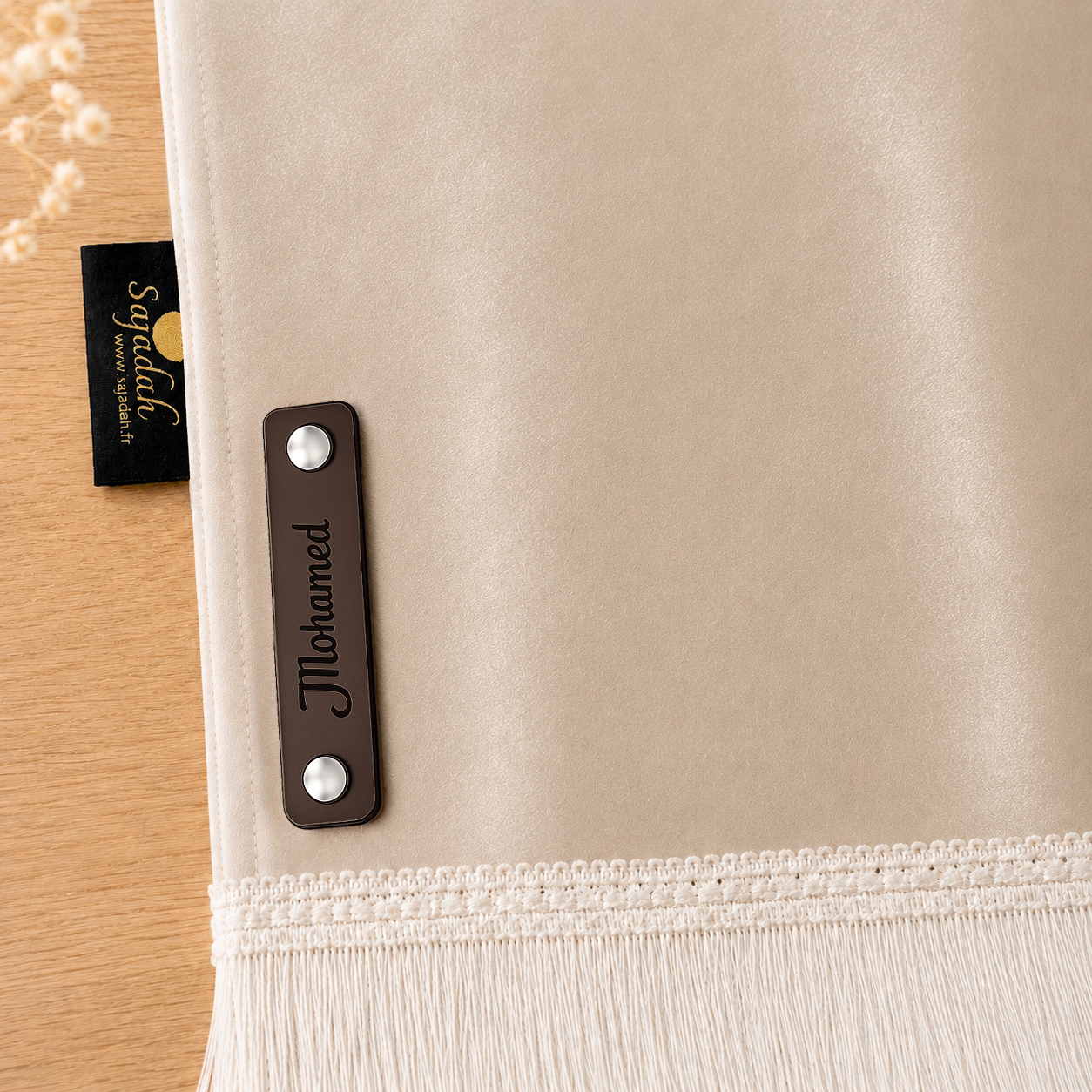 Zoom sur la personnalisation en cuir véritable de couleur chocolat portant votre prénom du tapis de prière Sajadah pour enfant beige Crème.