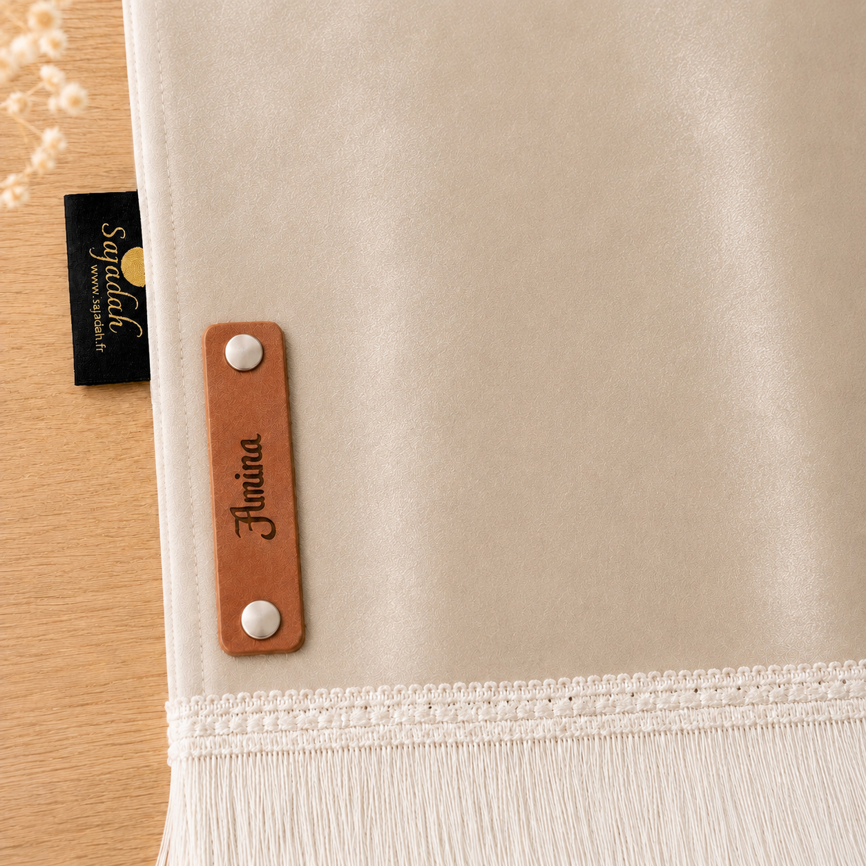 Zoom sur la personnalisation en cuir véritable de couleur marron portant votre prénom du tapis de prière Sajadah pour enfant beige Crème.